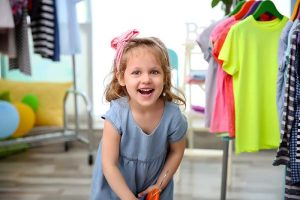 Cute baby girl in baby resale store with baby clothes on hangers